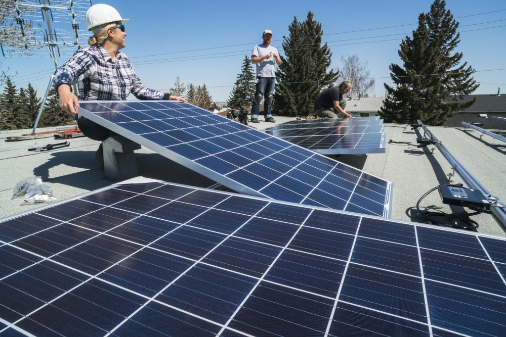 Woman installs a solar panel on the roof of a residential building.