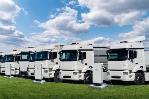 Row of electric semi trucks at charging stations for electric vehicles.