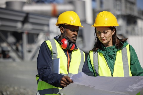 A Black man and a white woman review plans at an oil refinery. 
