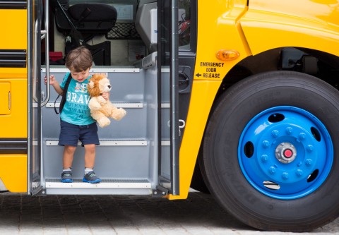 Child descending from electric school bus